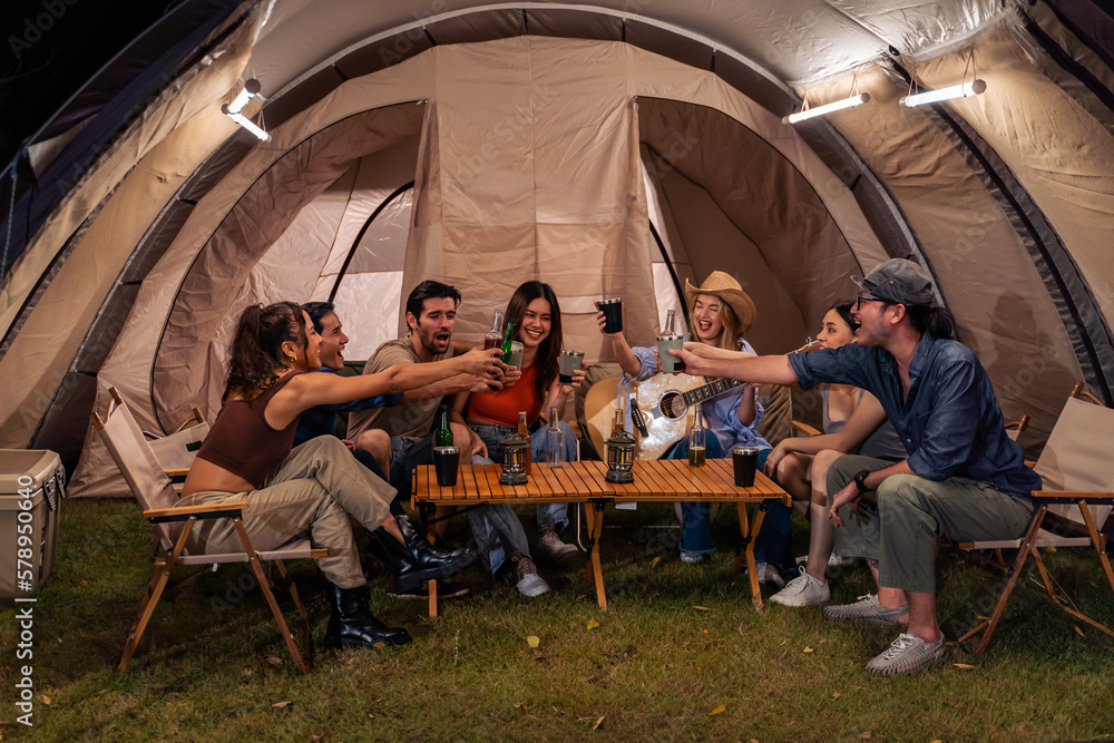 Group of diverse friend having outdoors camping party together in tent. 