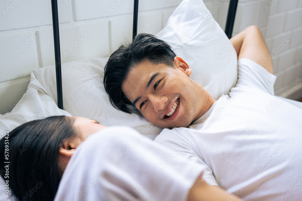 Asian new marriage couple lying down on bed and looking at each other. 