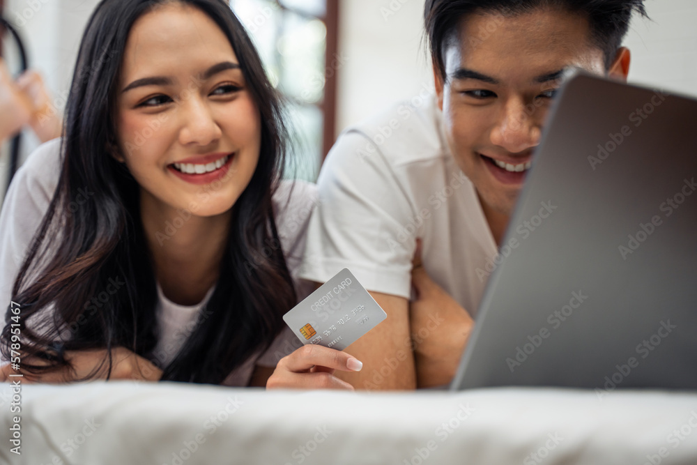 Asian attractive woman using laptop on bed with husband in the morning. 