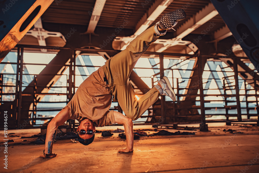 Young man break dancing on urban background, tattoo on hand