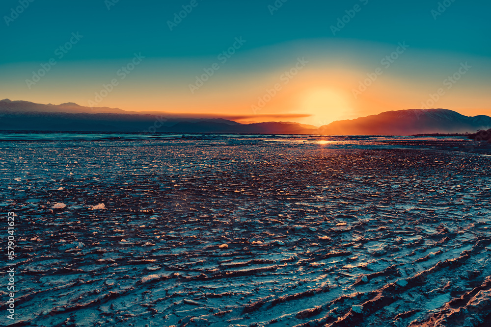 Frozen water in lake at cold winter weather, sunset light, Kyrgyzstan, Issyk-Kul