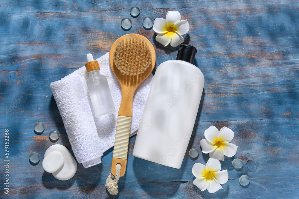 Composition with bath supplies, cosmetic products and flowers on color wooden background