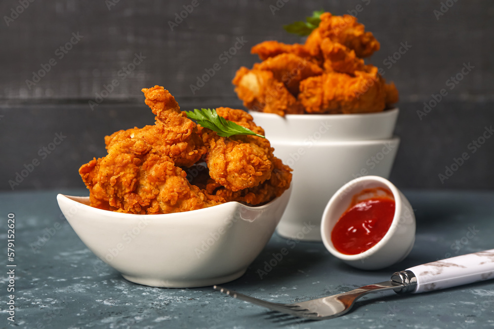 Bowls of tasty nuggets and sauce on dark table