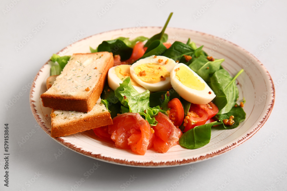 Plate of delicious salad with boiled eggs and salmon on grey background