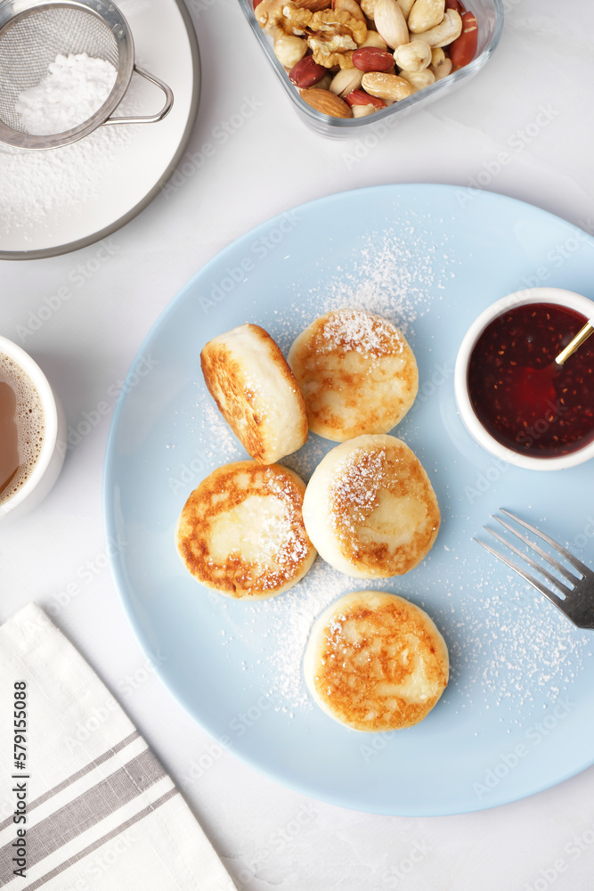 Plate with tasty cottage cheese pancakes and strawberry jam on light background, closeup