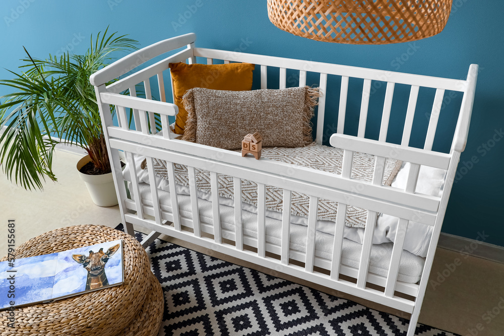 Baby crib with pillows and wooden toys in bedroom