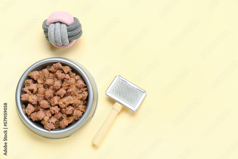 Bowl of wet pet food, grooming brush and cotton ball on color background