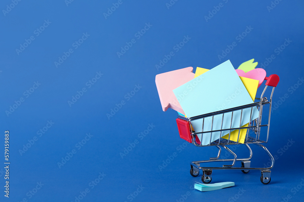 Shopping cart with different sticky notes on blue background