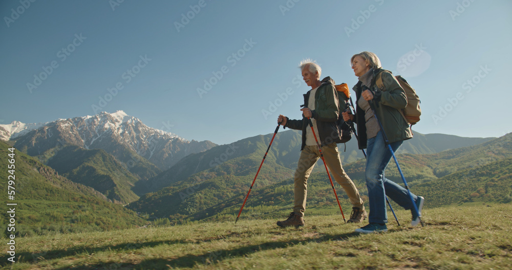 Mature caucasian couple on vacation, having a hike in spring mountains, spending time together after