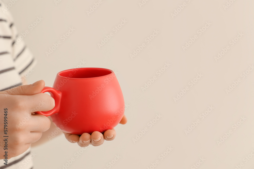 Woman holding red cup on beige background