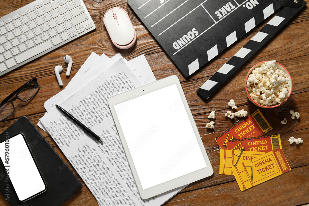 Movie clapper with tablet computer, keyboard, earphones and popcorn on wooden background