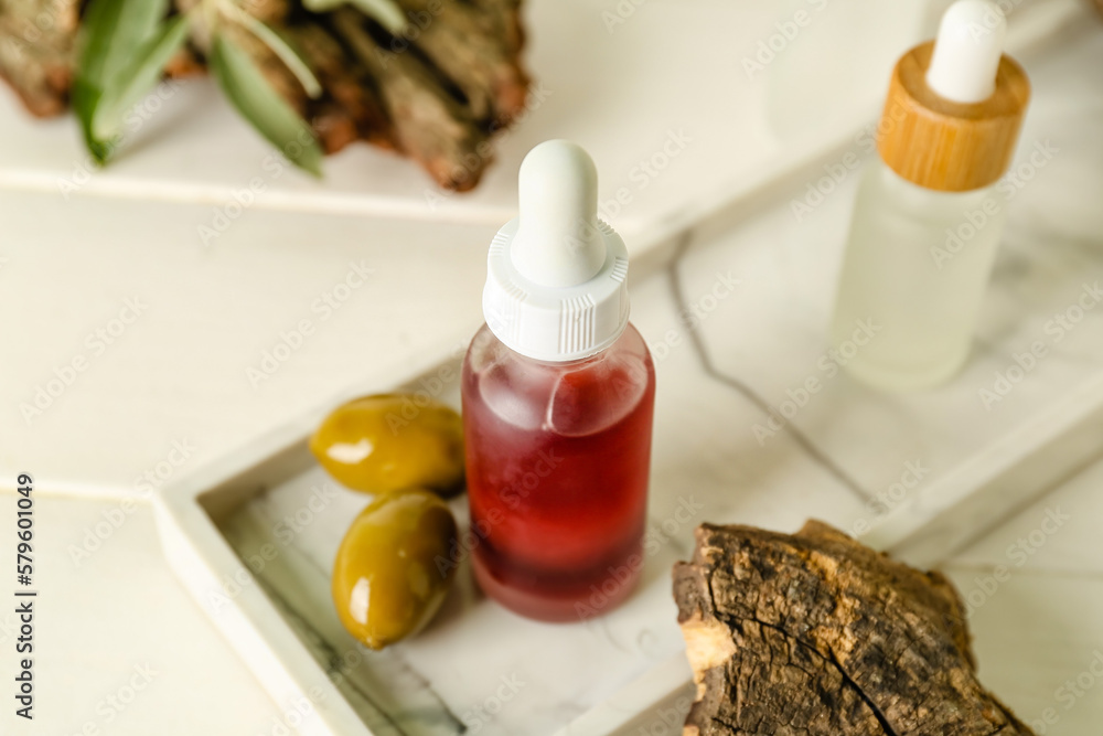 Bottle of olive essential oil on light wooden table