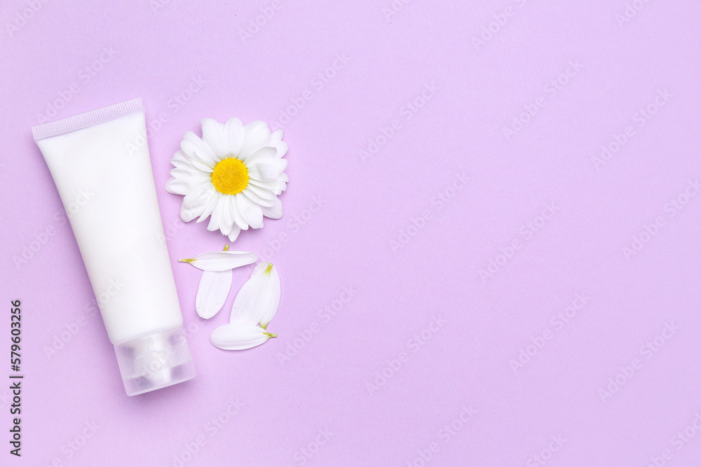 Tube of cosmetic product, chamomile flower and petals on lilac background