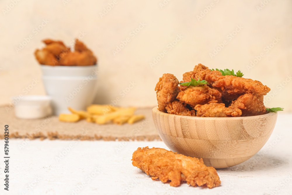 Wooden bowl of tasty nuggets on light table