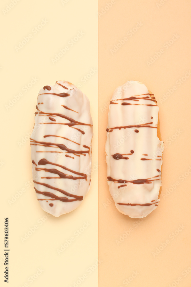 Tasty glazed eclairs on yellow and orange background