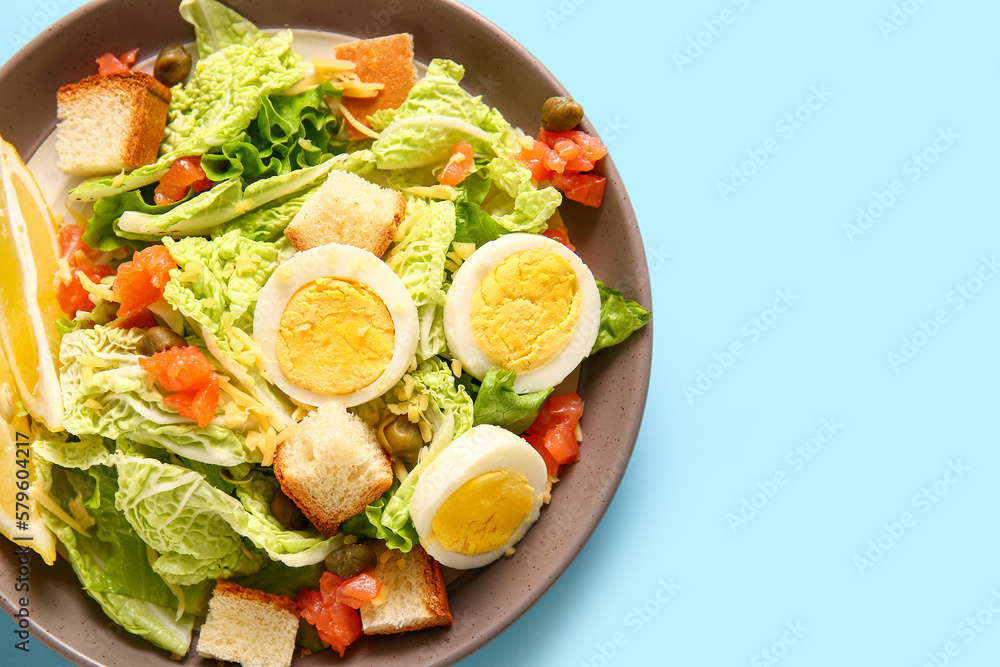 Plate of delicious salad with boiled eggs and salmon on blue background