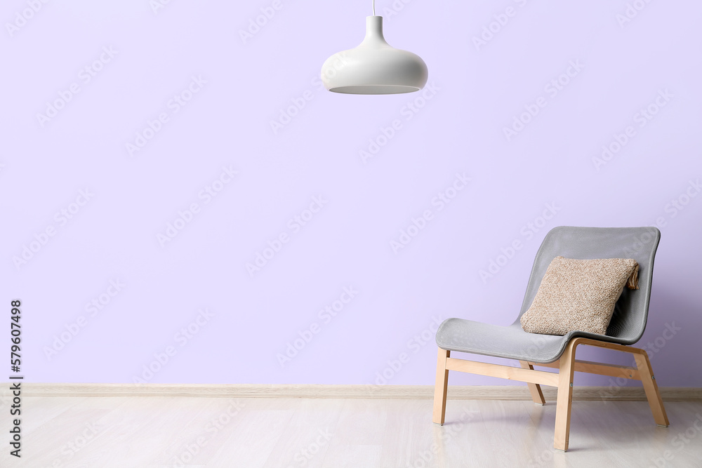 Stylish grey armchair near lilac wall