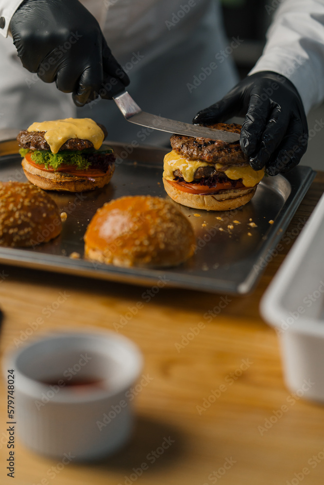 Chef prepares delicious hamburger in professional kitchen burger with beef patty cheese tomato fried