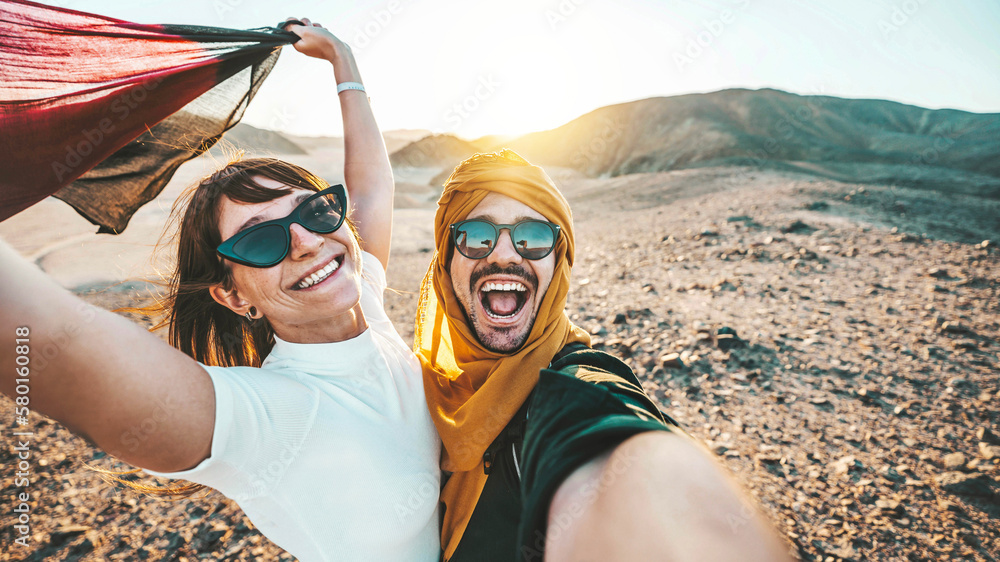 Happy couple of travelers taking selfie picture in rocky desert - Young man and woman having fun on 