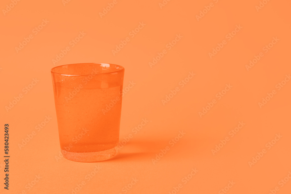 Glass of water on orange background