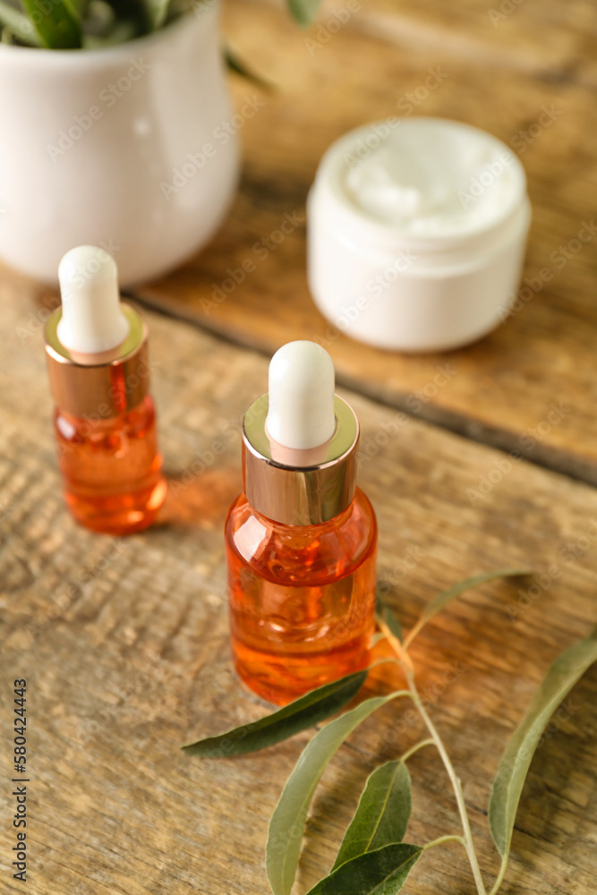 Bottles of olive essential oil on wooden background