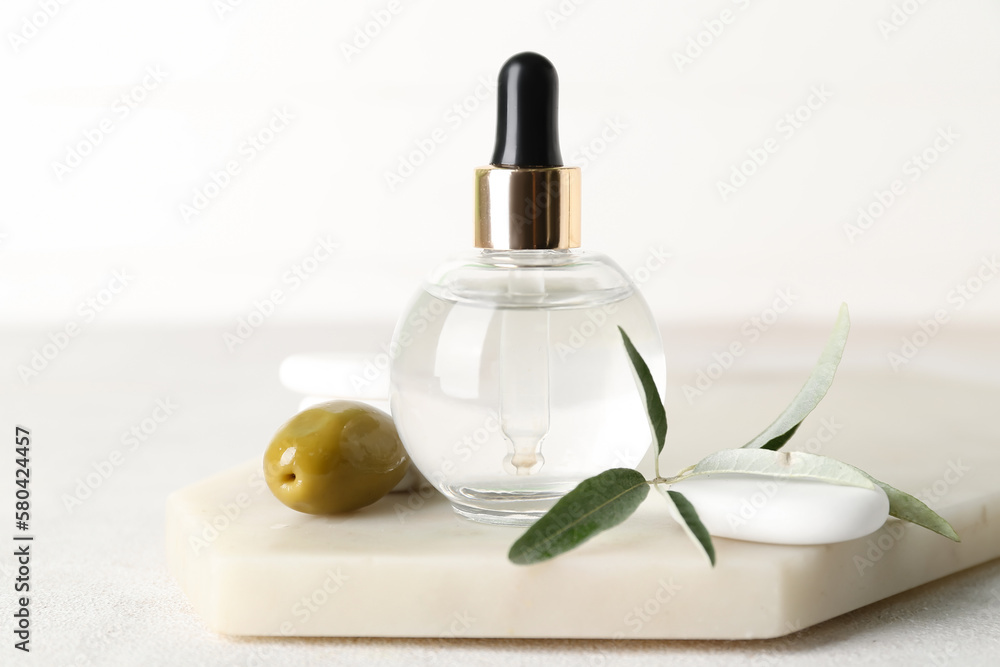 Board with bottle of olive essential oil on light background, closeup