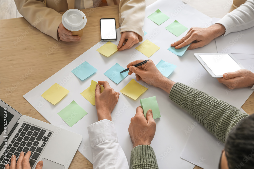 Group of people with sticky notes working on business plan at table in office, closeup