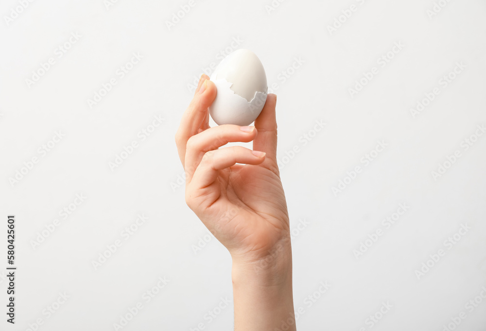 Woman with boiled egg on light background