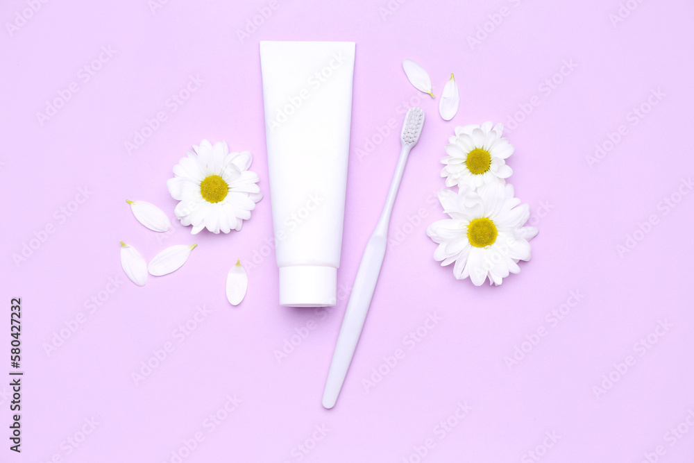 Composition with tube of toothpaste, toothbrush and chamomile flowers on lilac background