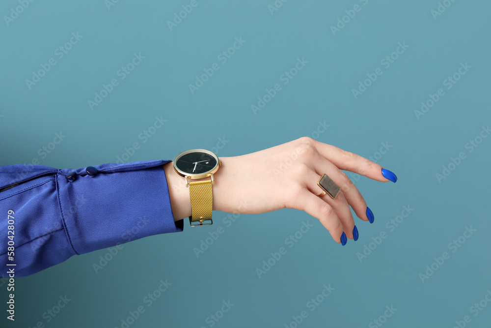 Woman with golden wristwatch on blue background