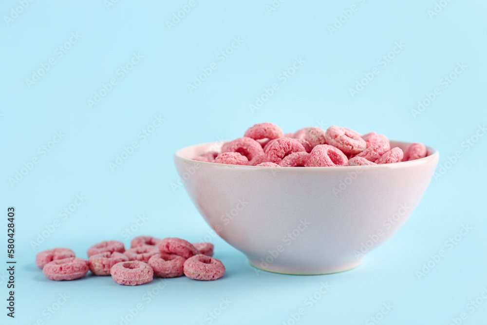 Bowl of pink cereal rings on blue background