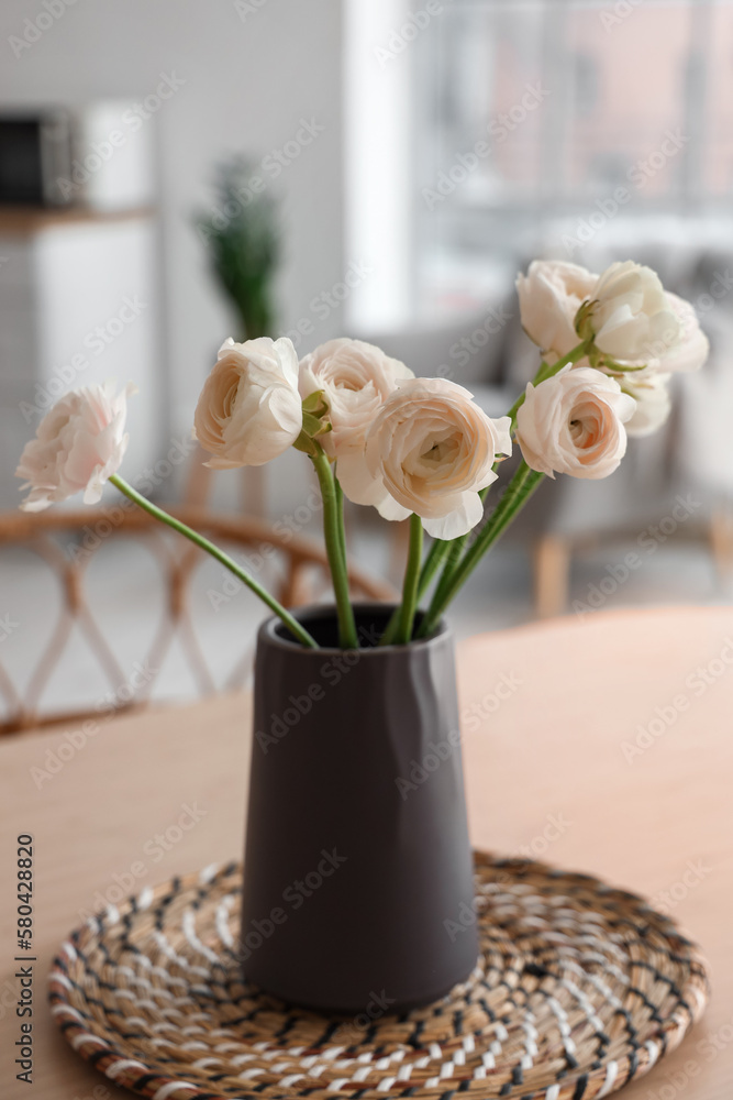 Vase with ranunculus flowers on dining table in kitchen, closeup