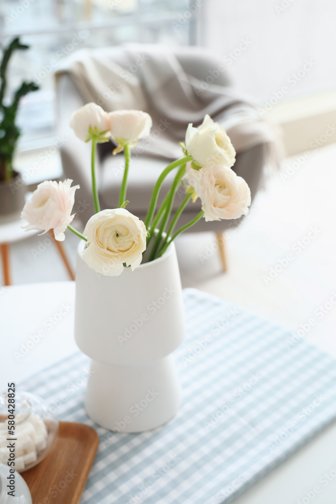 Vase with ranunculus flowers on dining table in kitchen, closeup