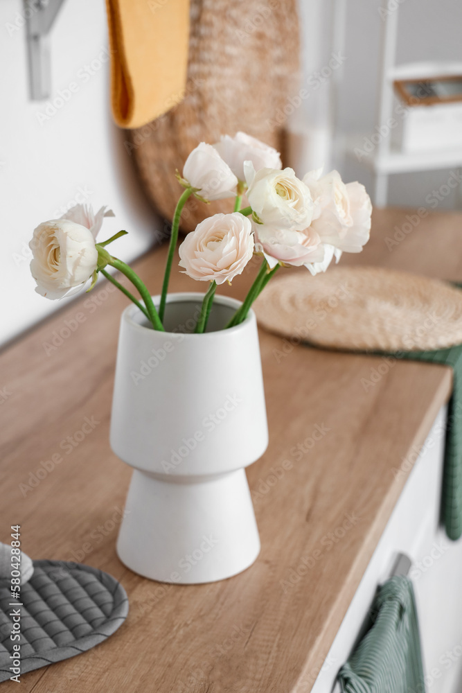 Vase with ranunculus flowers on counter in light kitchen