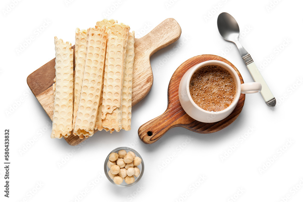 Board with delicious wafer rolls, hazelnuts and cup of coffee on grey background