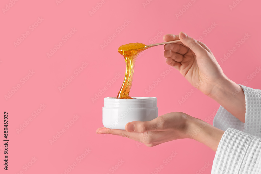 Hands with sugaring paste on pink background