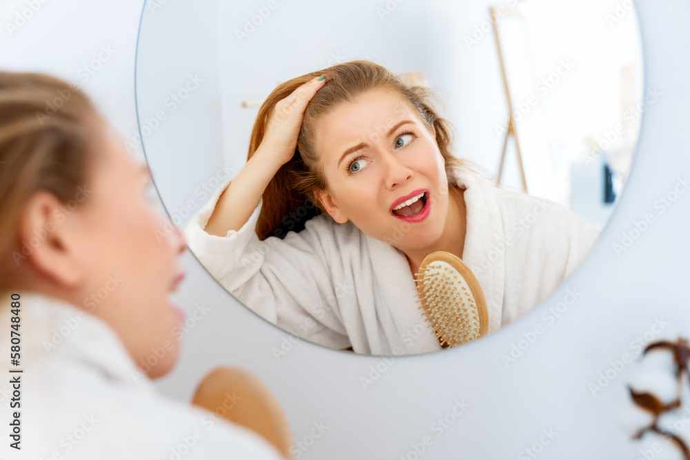 woman looking at scalp in mirror