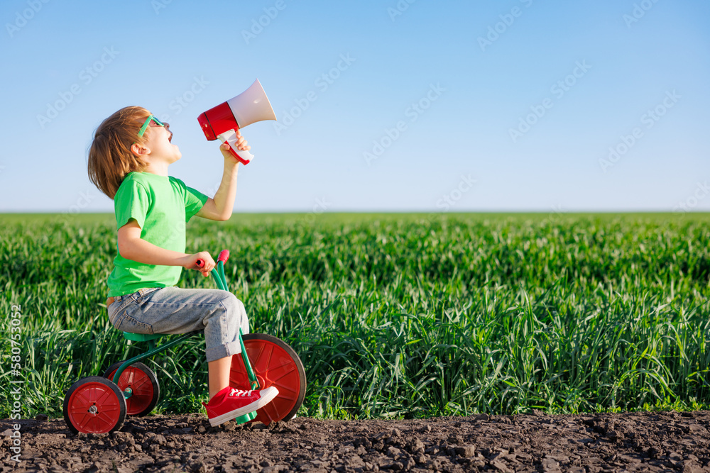 Child shouting through loudspeaker against blue summer sky