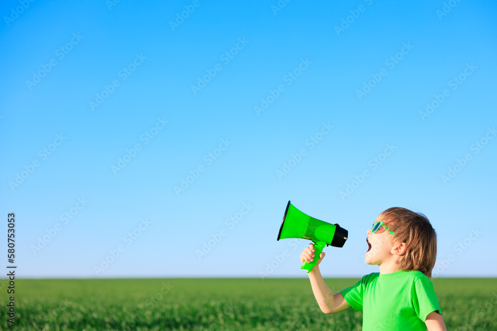 Happy child shouting through loudspeaker against blue summer sky