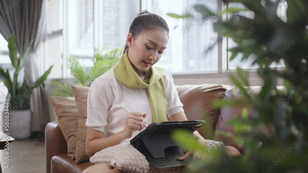 Asian woman using tablet to work at home.