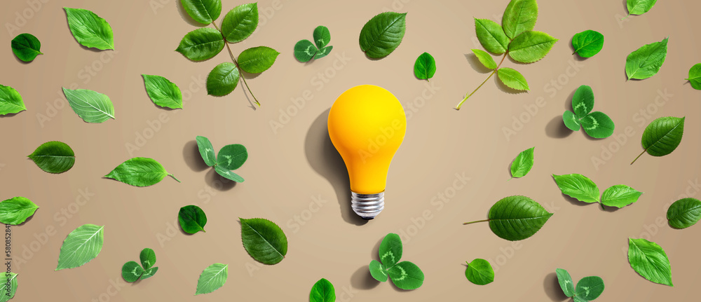 Yellow light bulb with green leaves - Flat lay