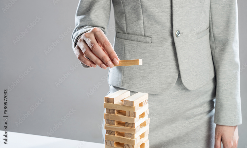 Business woman building tower from wooden blocks