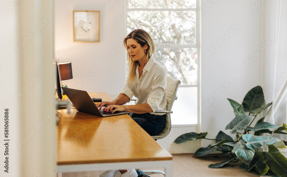 Female entrepreneur typing on a laptop in her office