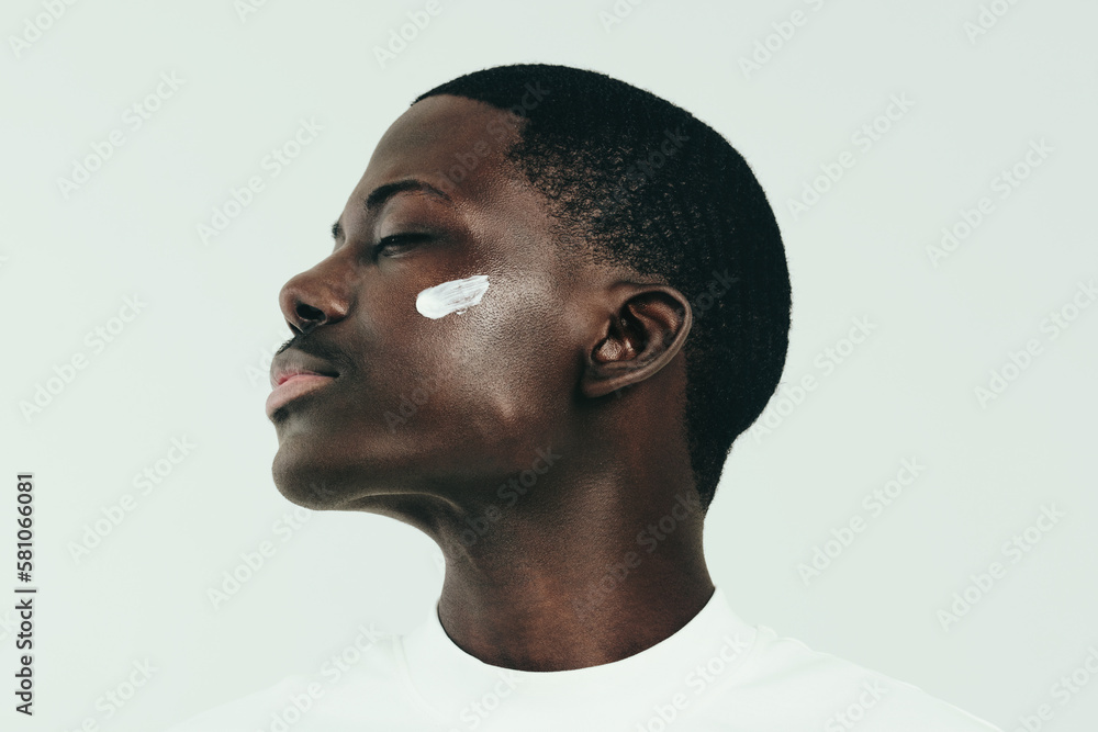 Young black man taking care of his skin with nourishing face cream