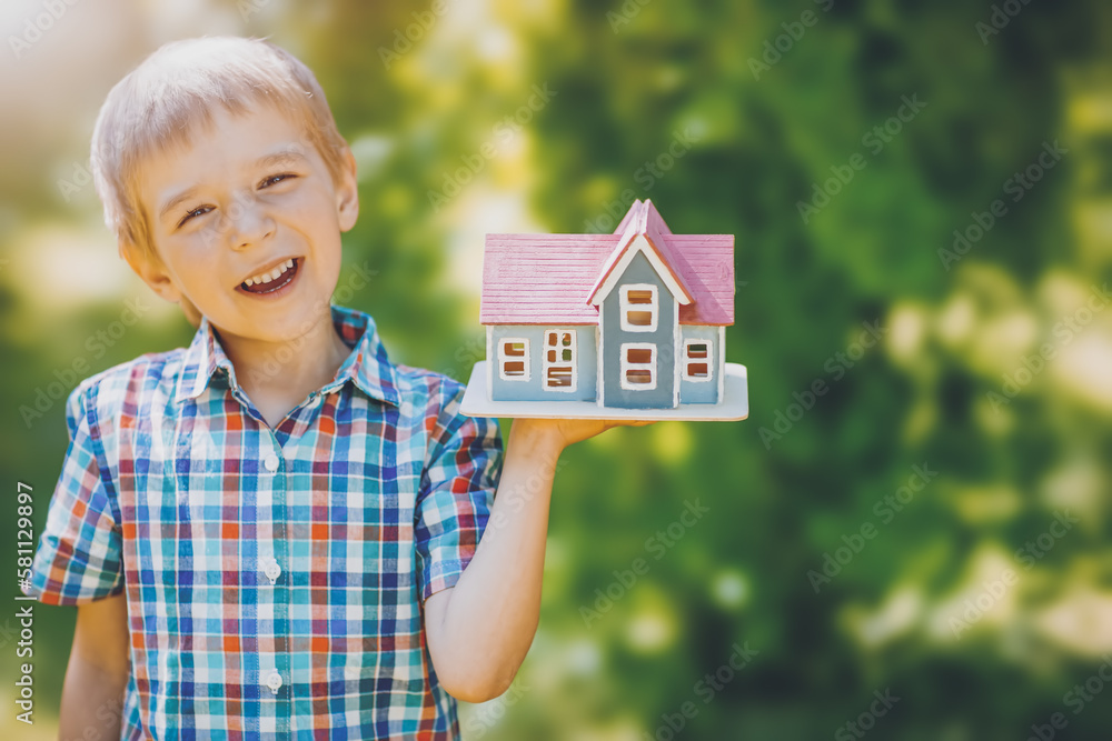 Little child holding in his hand a model of the house.