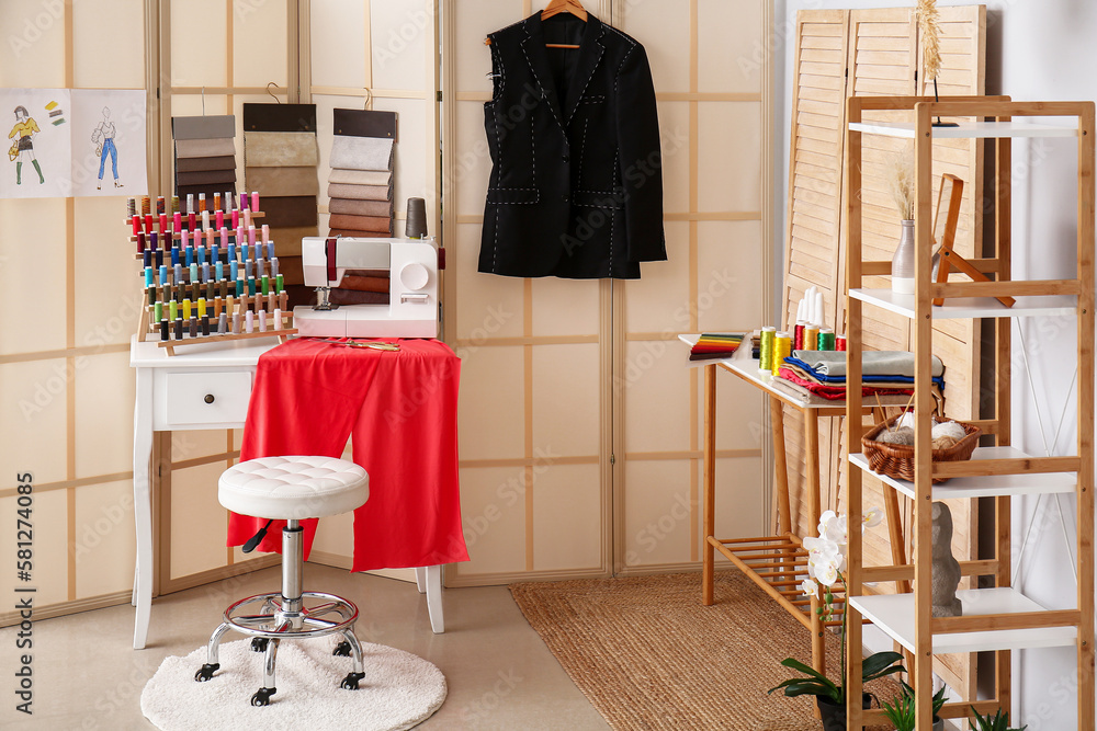 Interior of atelier with tailors workplace, fabric samples and thread spools