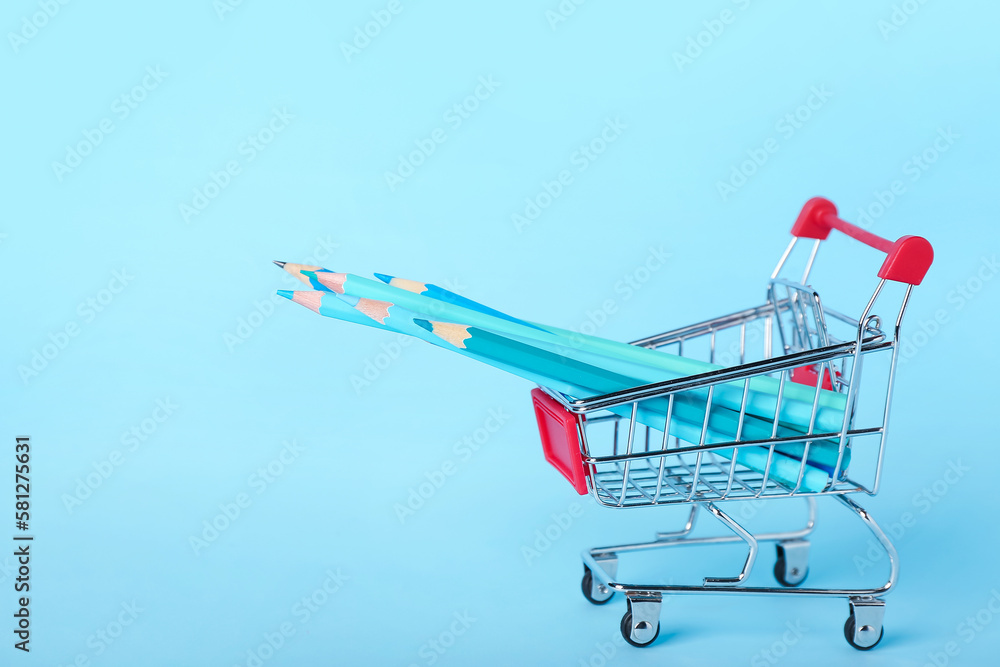 Shopping cart with pencils on blue background