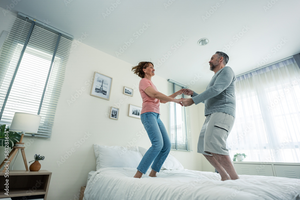 Caucasian senior couple dancing with music together in bedroom at home. 