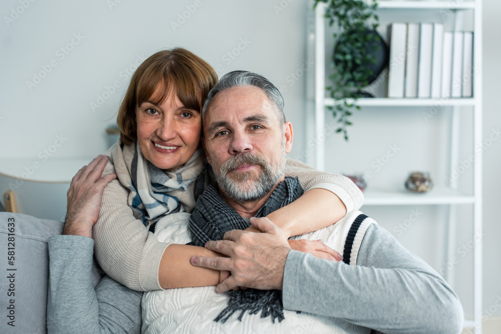 Portrait of Caucasian senior elderly couple sit on sofa in living room.