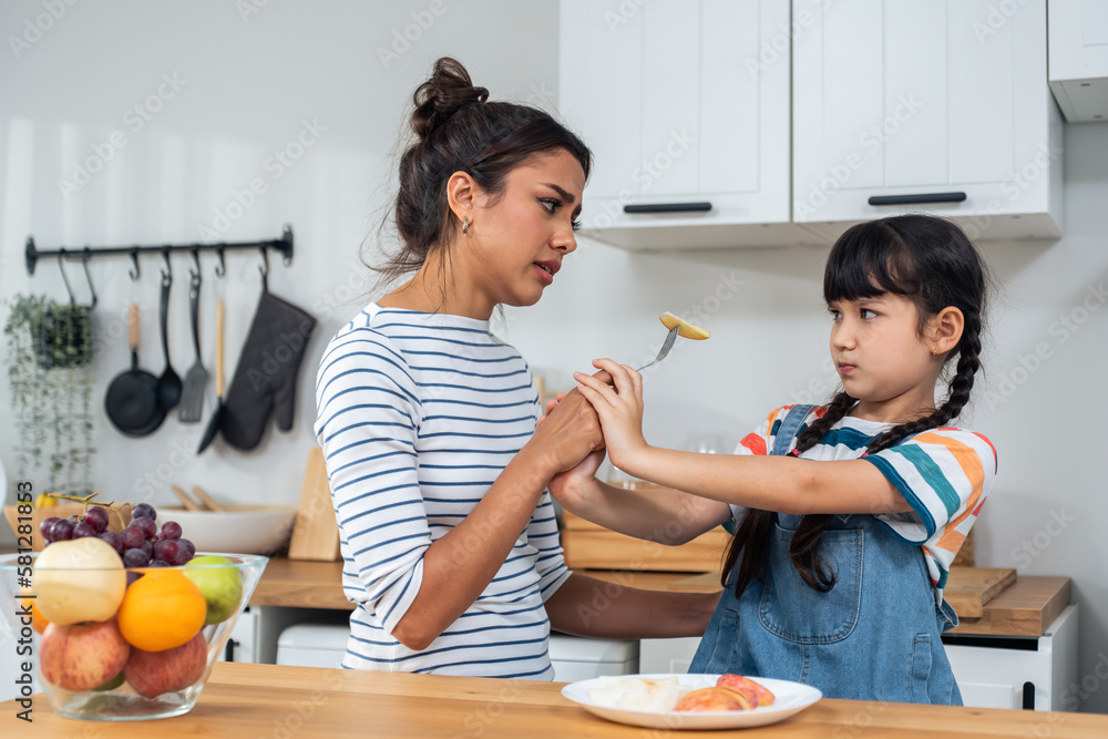 Caucasian mother teach and motivate young daughter eat green vegetable. 